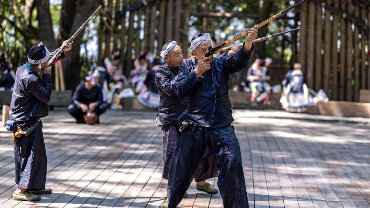 Basha Miao village men with traditional firearms and distinctive topknot hairstyles