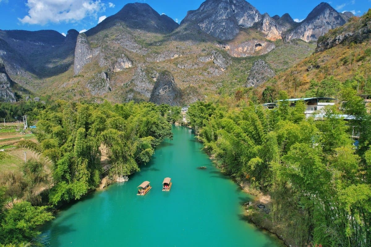 Bamboo raft floating on jade-green water between karst cliffs at Da-Xiao Jing